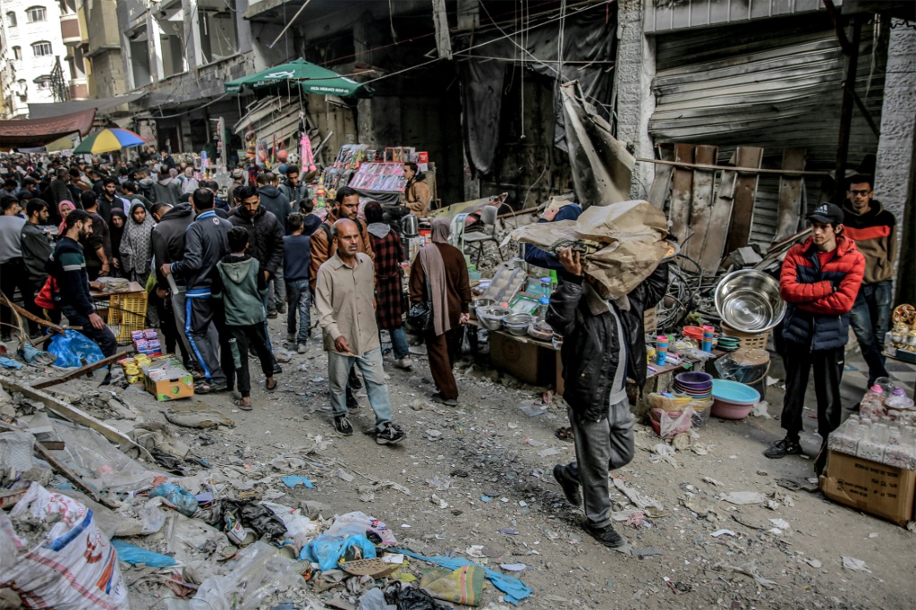 فلسطينيون يشترون من باعة في إحدى الأسواق وسط الدمار في مدينة غزة في 27 آذار مارس 2024 (ا ف ب)