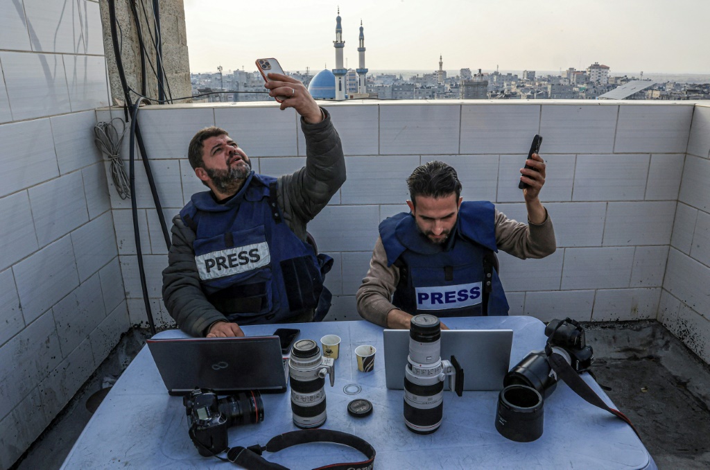 صحفيون فلسطينيون يحاولون الاتصال بالإنترنت باستخدام هواتفهم في رفح بجنوب قطاع غزة في 27 ديسمبر 2023 (ا ف ب)