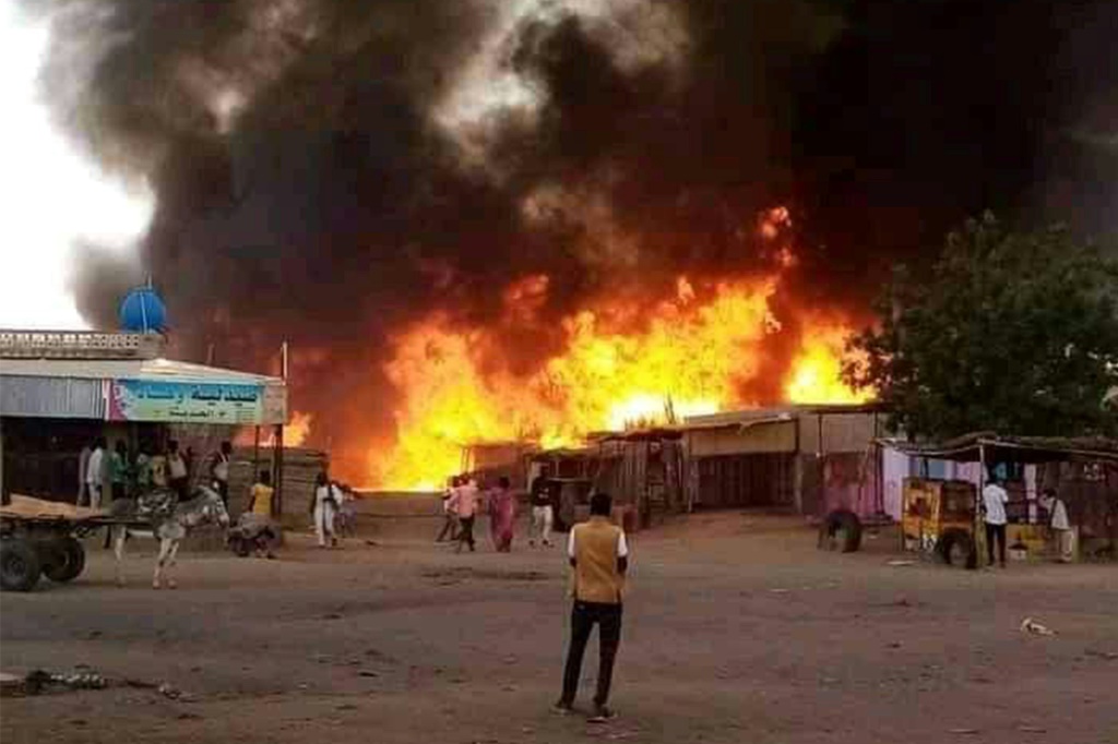 رجل يقف متفرجا بينما تشتعل النيران في منطقة سوق للماشية في الفاشر عاصمة ولاية شمال دارفور السودانية في 1 أيلول/سبتمبر 2023 في أعقاب قصف لقوات الدعم السريع (ا ف ب)