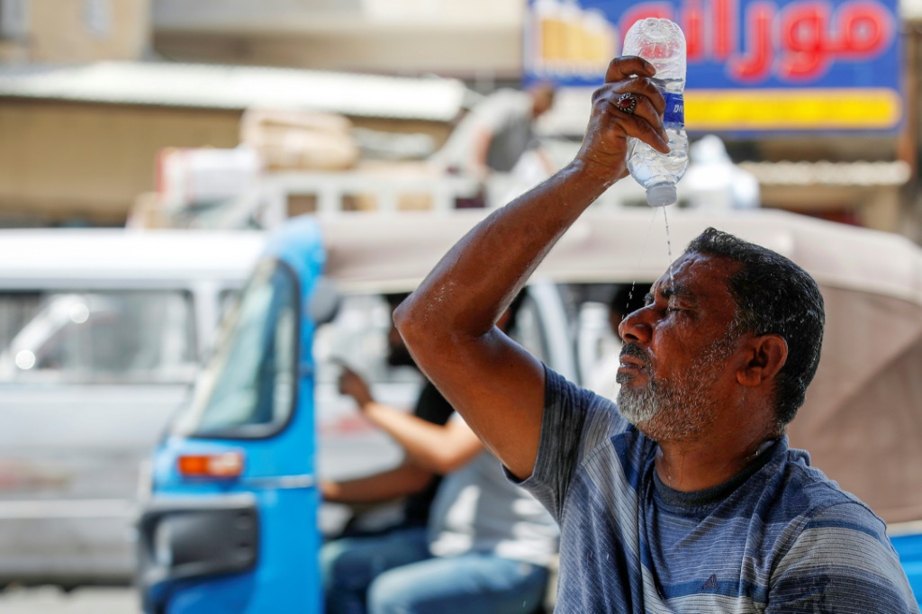 رجل يضع الماء على وجهه في بغداد ليقاوم درجات الحرارة المرتفعة في 13 آب أغسطس 2023 (ا ف ب)