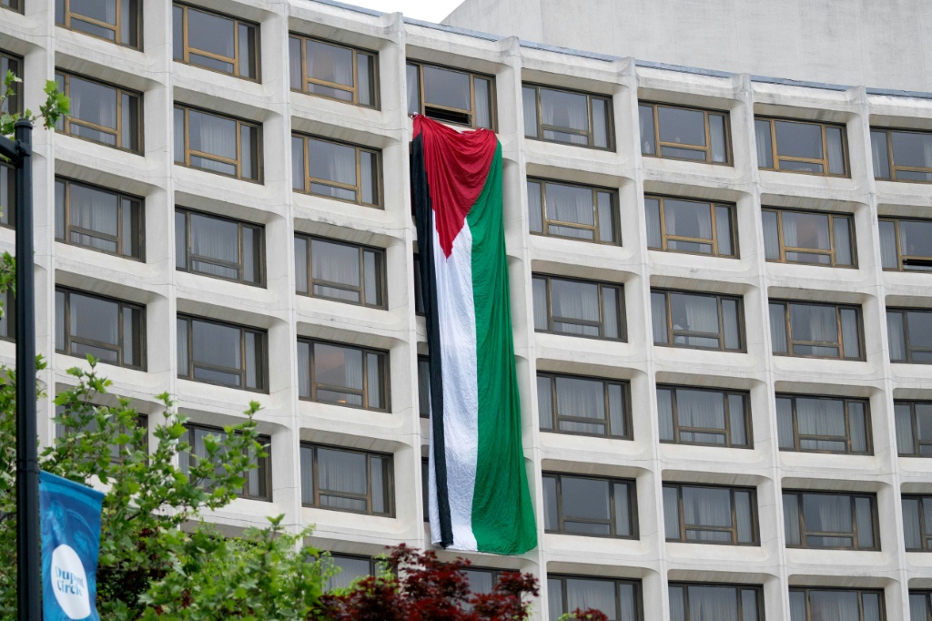 متظاهرون علقوا علما فلسطينيا على واجهة فندق هيلتون في واشنطن تزامنا مع إقامة العشاء السنوي لمراسلي البيت الأبيض في 27 نيسان/أبريل 2024 (ا ف ب)