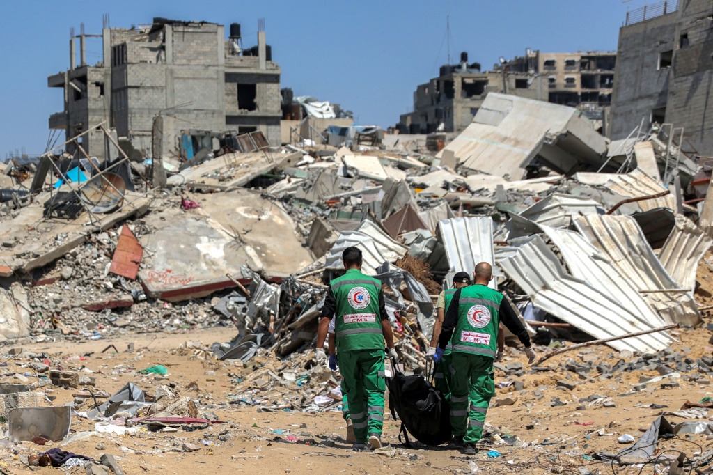 مسعفون فلسطينيون ينقلون جثث القتلى التي عثر عليها في محيط مستشفى الشفاء بمدينة غزة (أ ف ب)   